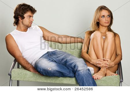 Молодая пара, сидя на зеленом диване