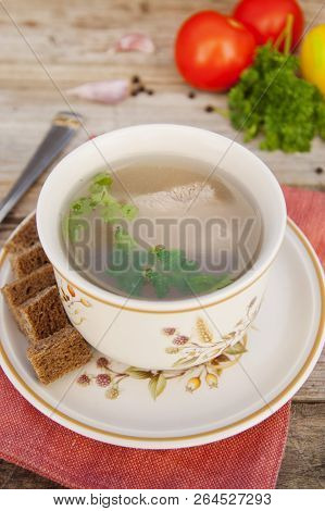 Clear Beef Broth, Bouillon In White Bowl And Vegetables On Wooden Table. Rustic Style.