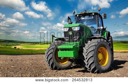 Russia, Krasnodar region, Kushevsky district.16.10.2018.   Modern, green tractor in the spring field work on the background of a beautiful rural landscape.