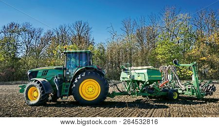 Russia, Krasnodar region, Kushevsky district.16.10.2018.   Modern, green tractor in the spring field work on the background of a beautiful rural landscape.