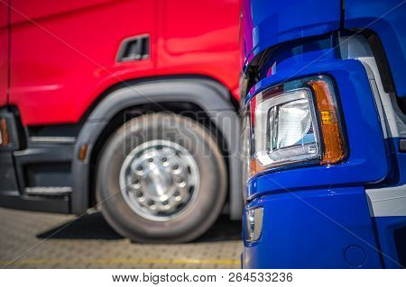 New And Pre Owned Trucks For Sale Closeup Photo. Blue And Red Euro Semi Trucks. Transportation Indus