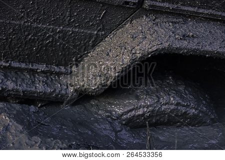 Fragment Of Car Stuck In Dirt, Close Up. Wheel In Deep Puddle Of Mud Overcomes Obstacles. 4x4 Racing