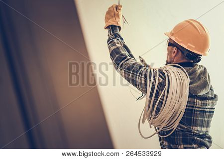 Electrician In Yellow Hard Hat With Cable Working In The Construction Area.