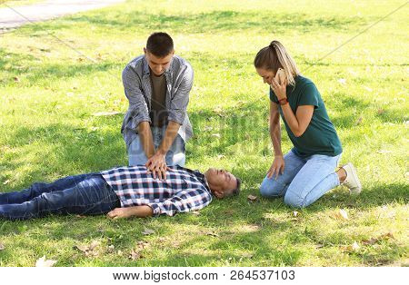 Passersby Helping Unconscious Man Outdoors. First Aid