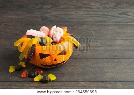 Trick Or Treat Pumpkin Jack With Colorful Candies On Wooden Background