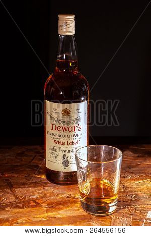 LVIV, UKRAINE - DECEMBER 04: Bottle of Dewars whisky and glass on wooden shelf on December 04, 2017 in Lviv