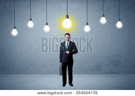 Handsome businessman in an empty space with bulbs above and uninspired face