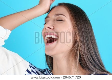 Portrait Of Beautiful Young Woman Bursting Into Laughter On Color Background