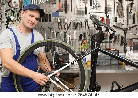 Professional Mechanic Repairing Bicycle In Modern Workshop