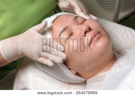 The Hands Of A Beautician In Gloves Wash The Face Of A Muslim Woman With Soap. Happy Beautiful Orien