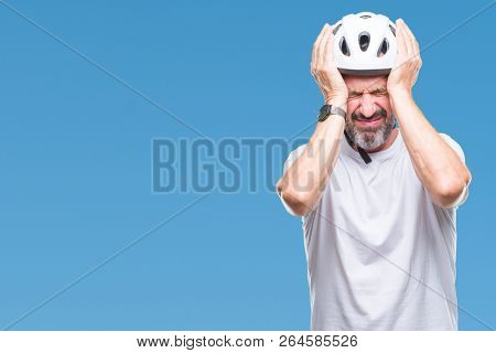 Middle age senior hoary cyclist man wearing bike safety helment isolated background suffering from headache desperate and stressed because pain and migraine. Hands on head.