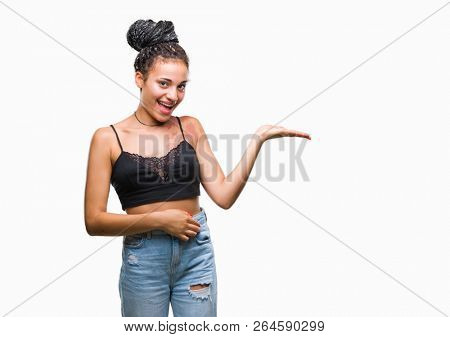 Young braided hair african american with pigmentation blemish birth mark over isolated background smiling cheerful presenting and pointing with palm of hand looking at the camera.