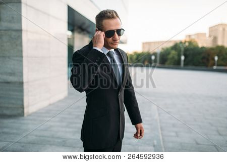 Male bodyguard talking by security earpiece