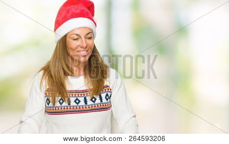 Middle age adult woman wearing winter sweater and chrismat hat over isolated background celebrating surprised and amazed for success with arms raised and open eyes. Winner concept.