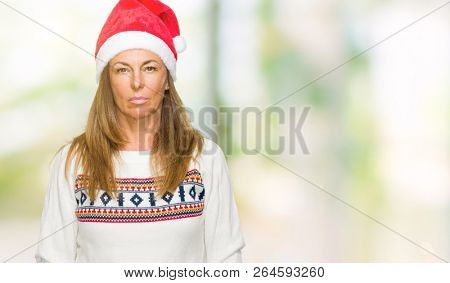 Middle age adult woman wearing winter sweater and chrismat hat over isolated background with serious expression on face. Simple and natural looking at the camera.