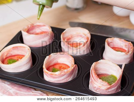 Cooking Tasty Bacon Egg Muffins. Pouring Sauce Pesto In Cups From Bacon With Bread And Tomato Slices
