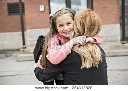 A Girl Child And His Mother Hugging Outside At School