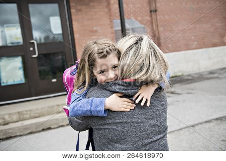 A Girl Child And His Mother Hugging Outside At School
