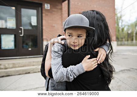 A Boy Child And His Mother Hugging Outside At School