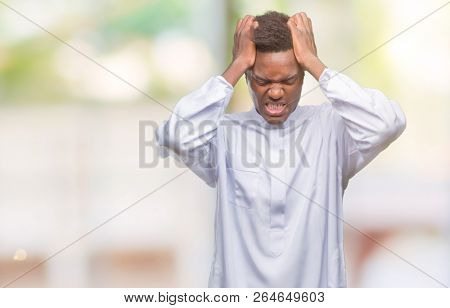 Young arabic african man wearing traditional djellaba over isolated background suffering from headache desperate and stressed because pain and migraine. Hands on head.