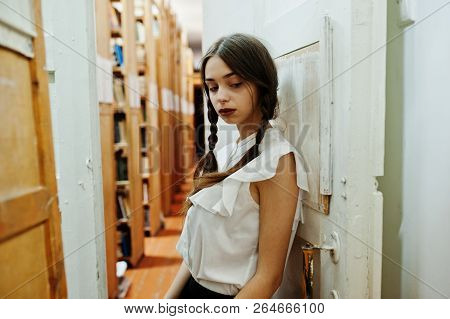 Girl With Pigtails In White Blouse At Old Library.