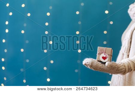 Woman Holding A Christmas Gift Box On A Shiny Light Dark Blue Background