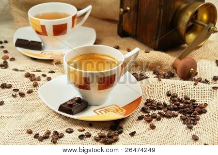 Kaffeetasse umgeben von Kaffee Körner und Kaffeemühle im Hintergrund