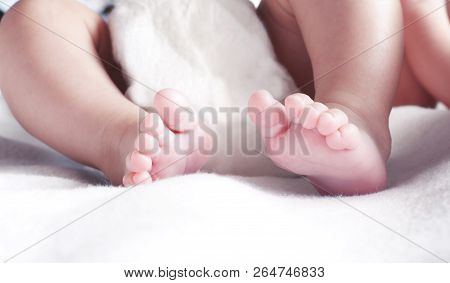 Legs Of A Newborn Baby Lying On The Bed. Toning And Blur. Selective Focus