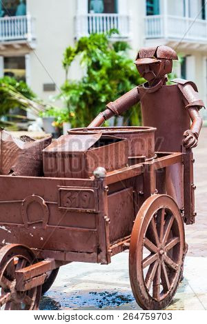 Cartagena De Indias, Colombia - August, 2018: Sculpture Of A Man With A Traditional Wheelbarrow At T