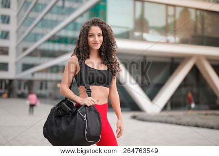 Beautiful exotic woman in a sporty outfit and with a duffle bag.