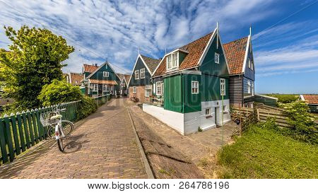 Characteristic Dutch Village Scene With Colorful Wooden Houses And Bridge With Dike Over Canal On Th