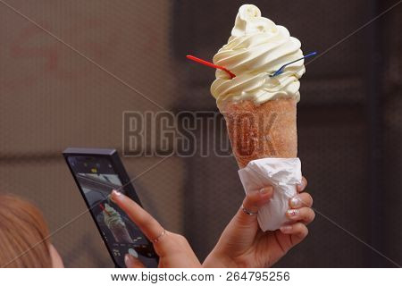PRAGUE, CZECH REPUBLIC - SEPTEMBER 14, 2018: Woman make photo of Trdelnik with ice cream. This Czech traditional spit cake with various fillings is very popular street food among tourists