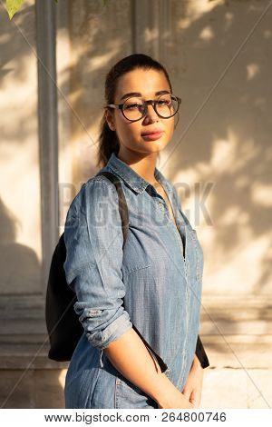 Young Attractive Bespectacled Woman Looking At The Camera And Smiling.