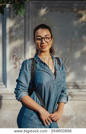 Young Attractive Bespectacled Woman Looking At The Camera And Smiling.