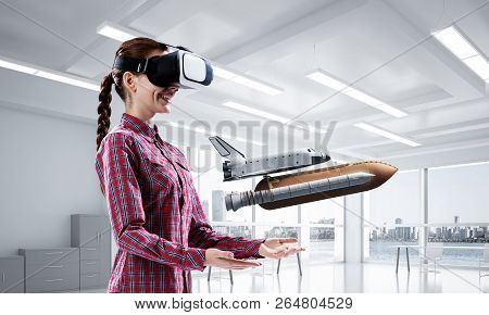 Young Caucasian Woman In Modern Office Interior Trying Virtual Reality Helmet And Viewing Space Shut