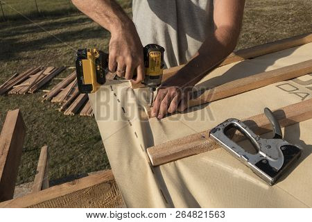 Roof Construction Building. Man Using Electrical Scredriver To Attach Construction Elements.