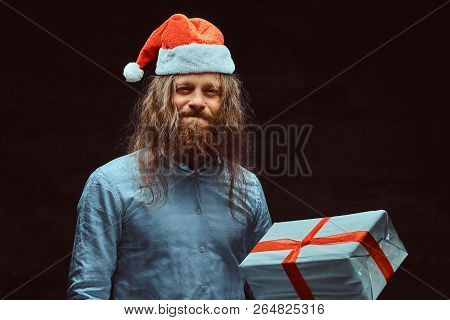 Angry Male With Long Hair And Beard In Blue Shirt Holds Gift Box.