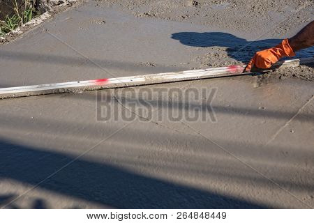 Worker Using A Wooden Spatula For Cement After Pouring Ready-mixed Concrete On Steel Reinforcement T
