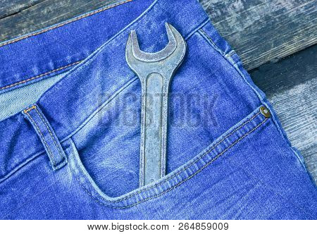 Large Metal Wrench In The Pocket Of Blue Jeans Pants. Construction Tool. Plumber