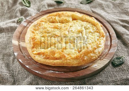 Megrelian Khachapuri Made From a Delicious Tender Dough with Melted Burnt Imeretian Cheese and Butter Close Up. Traditional Most Common Circular Hachapuri Topped with Lots of Grated Cheeses