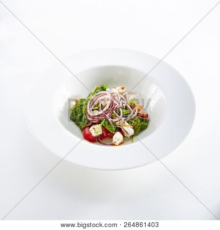 Green Salad with Goat Cheese, Spinach, Tomato and Red Onion Rings Isolated on White Background. Restaurant Starter Menu with fresh Spinacia and Chard Leaves, Tomatoes, Greens, Spices Close Up