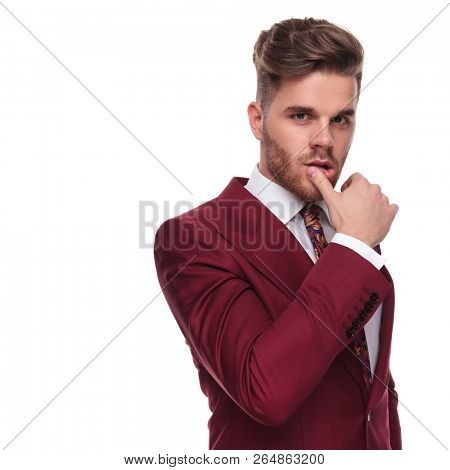 portrait of seductive elegant man wiping his lips with thumb while standing on white background