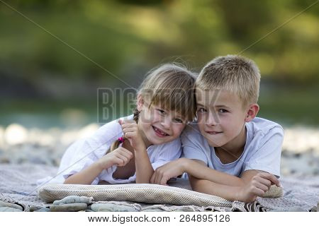 Two Young Happy Cute Blond Smiling Children, Boy And Girl, Brother And Sister Laying Embraced On Peb