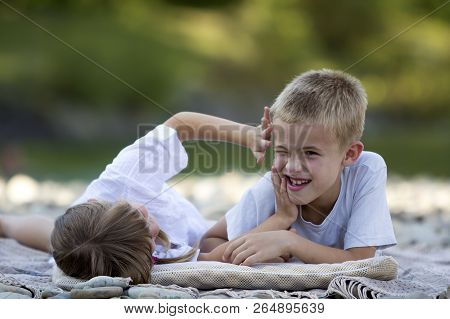 Two Young Happy Cute Blond Laughing Children, Boy And Girl, Brother And Sister Having Fun On Pebbled
