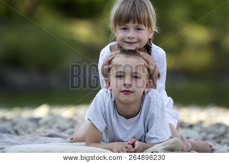 Two Young Happy Cute Blond Smiling Children, Boy And Girl, Brother And Sister Laying Embraced On Peb
