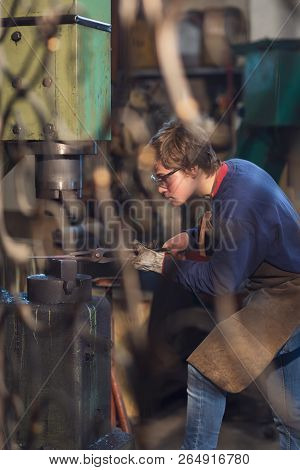 Young Blaksmith Working With Red Hot Metal In A Workshop