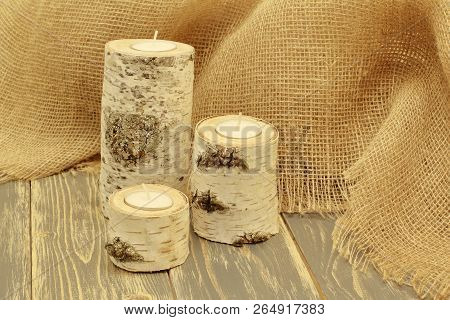 Original Birch Candlesticks Against A Background Of Coarse Jute Fabric. Black Wooden Background. Int