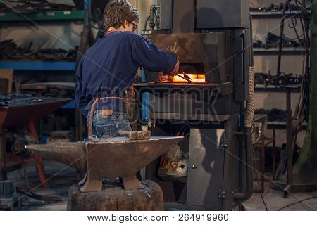 Young Blaksmith Working In A Metalworking Workshop