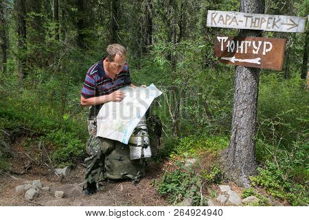Tourist With A Map Near The Signs. Inscriptions Tungur Village, Kara Turek Mountain.