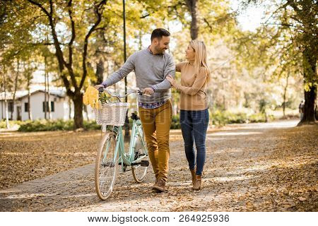 Active Young Couple Enjoying Romantic Walk With Bicycle In Golden Autumn Park